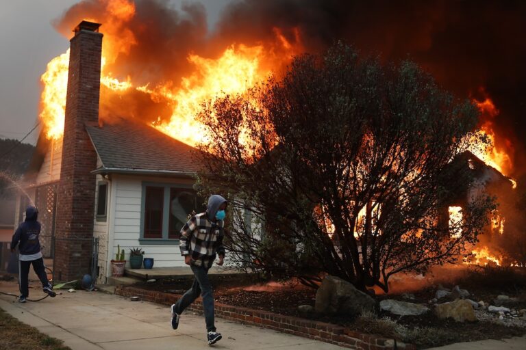 People attempt to save a neighboring home from catching fire during the Eaton Fire on January 8, 2025 in Altadena, California. (Photo by Mario Tama/Getty Images)
