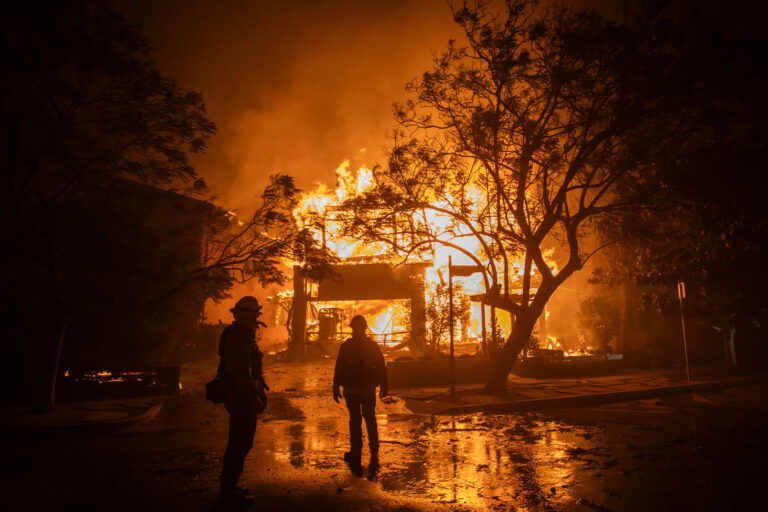 Firefighters watch the flames from the Palisades Fire burning a home during a powerful windstorm on January 8, 2025 in the Pacific Palisades neighborhood of Los Angeles, California. (Apu Gomes/Getty Images)