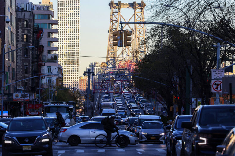 Pedestrians, cyclists and cars move along Delancey Street, with the Williamsburg Bridge in the background, in the Manhattan borough of New York on November 13, 2024. (CHARLY TRIBALLEAU/AFP via Getty Images)
