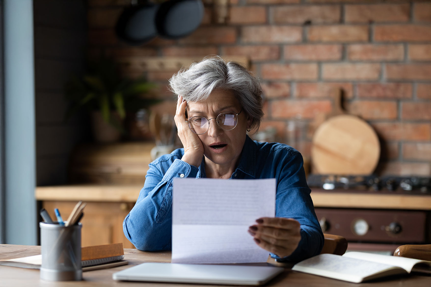 Mature woman looking at documents in shock (Getty Images/fizkes)
