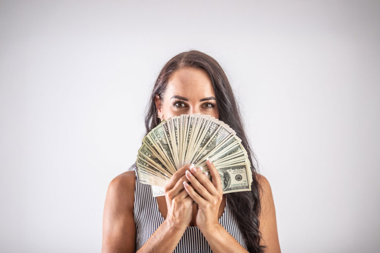 Woman looking through dollar bills (Getty Images/SimpleImages)