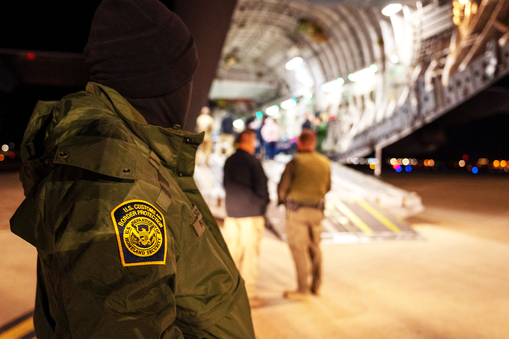 A U.S. Customs and Border Protection agent watches as illegal immigrants are loaded onto a C-17 Globemaster III at Tucson International Airport in Tucson, on January 23, 2025 in Tucson, Arizona. (Senior Airman Devlin Bishop/U.S. Department of Defense via Getty Images)