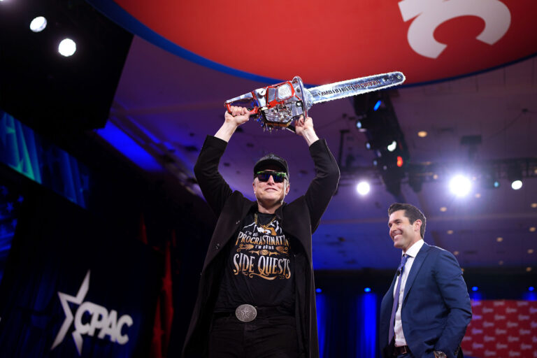 CEO of Tesla and SpaceX Elon Musk wields a chainsaw as he leaves the stage alongside Newsmax anchor Rob Schmitt at the Conservative Political Action Conference (CPAC) at the Gaylord National Resort Hotel And Convention Center on February 20, 2025 in Oxon Hill, Maryland. (Andrew Harnik/Getty Images)