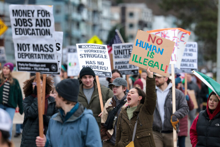 People hold signs during a march against Immigration and Customs Enforcement (ICE) entitled "Get our Gente Out of Guantanamo Bay!" in Seattle, Washington, on February 8, 2025. (JASON REDMOND/AFP via Getty Images)