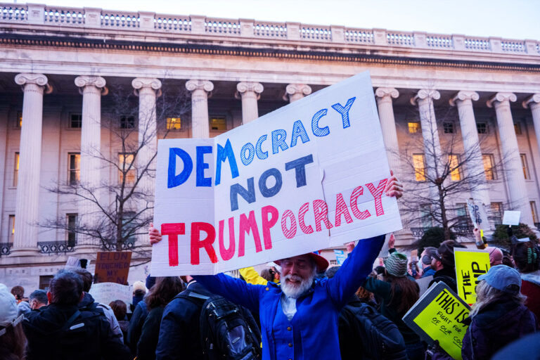 A protester holds a sign reading "Democracy Not Trumpocracy" during a rally in front of the U.S. Treasury Department in Washington, D.C., on February 4, 2025. (HOSSEIN FATEMI/Middle East Images/AFP via Getty Images)