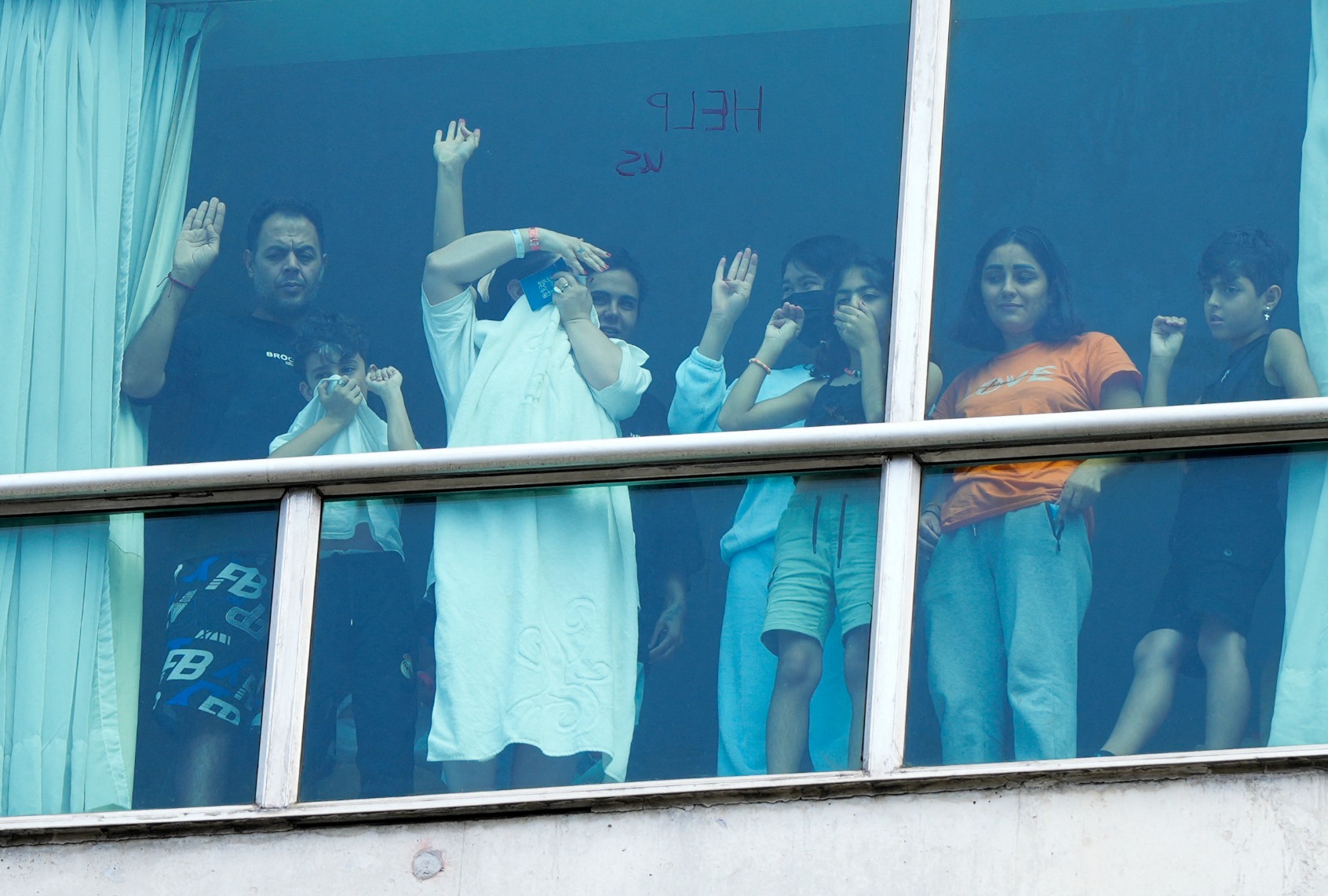 Migrants deported from the US gesture as they look out the window of the Decapolis Hotel where they are temporarily staying in Panama City, on February 18, 2025. (ARNULFO FRANCO/AFP via Getty Images)