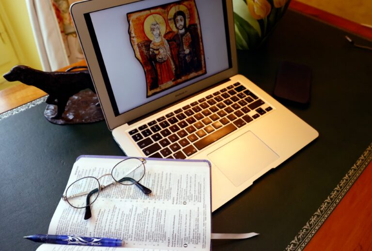 Laptop and open bible with glasses (Godong/Universal Images Group via Getty Images)