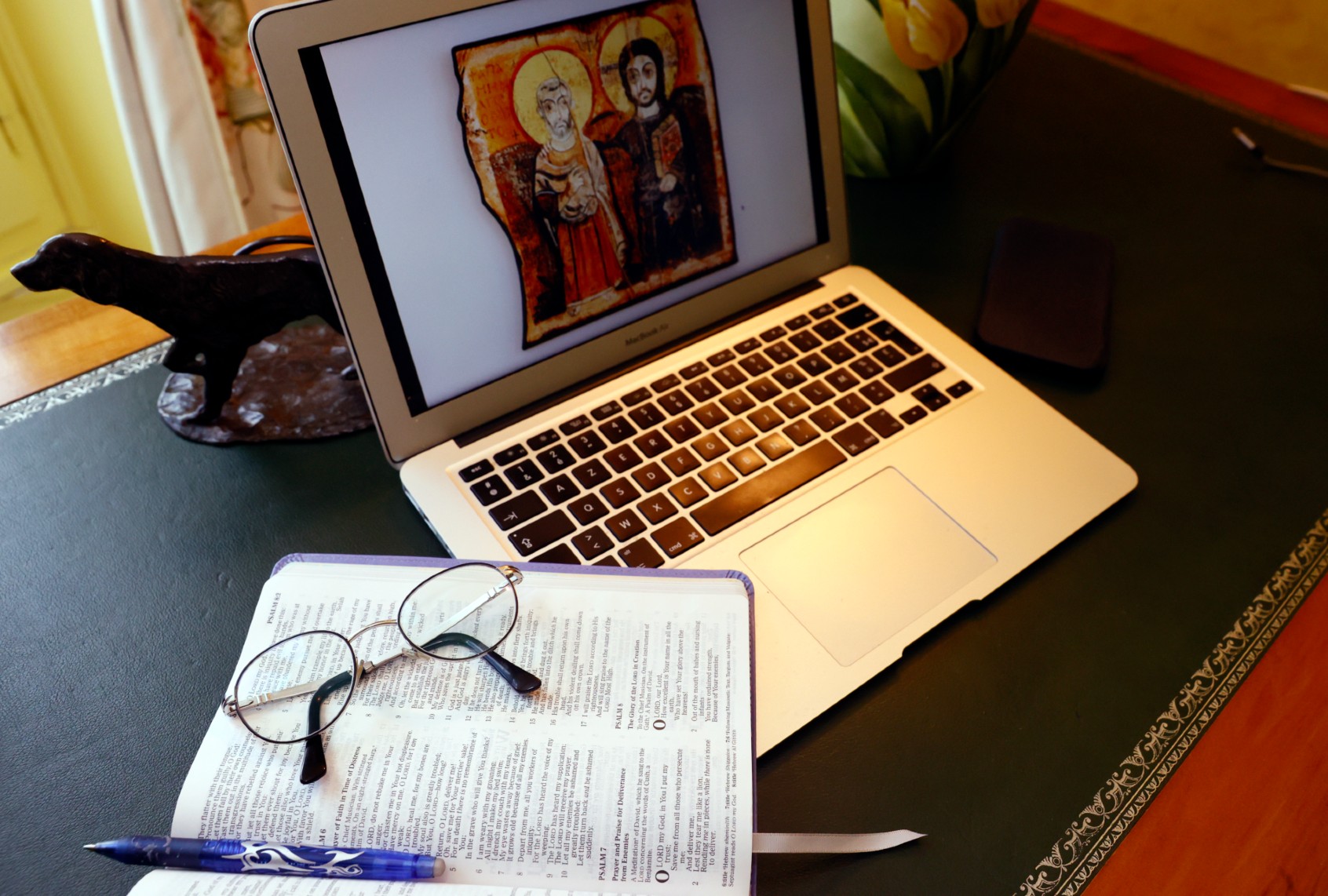 Laptop and open bible with glasses (Godong/Universal Images Group via Getty Images)
