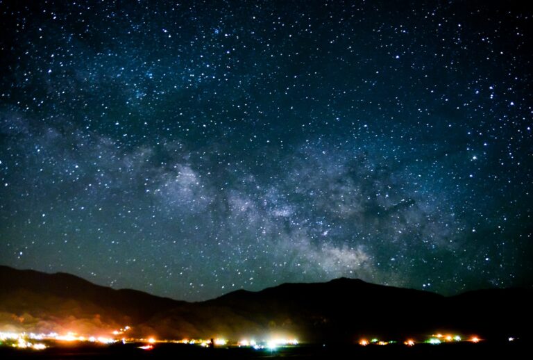 A small town glows beneath a starry sky. (harpazo_hope / Getty Images)