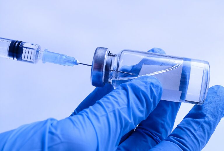 A doctor in medical protective gloves takes a vaccine from a glass ampoule into a syringe. (Aleksandr Zubkov / Getty Images)