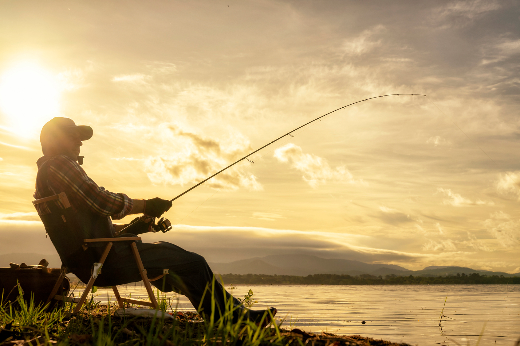 Man fishing at the waterfront (Getty Images/Virojt Changyencham)