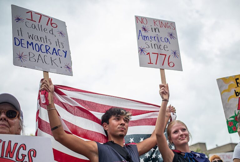 A protester holds a US flag and a placard during a nationwide "No Kings" rally in Louisville, Kentucky, on June 14, 2025 (LEANDRO LOZADA/AFP via Getty Images)