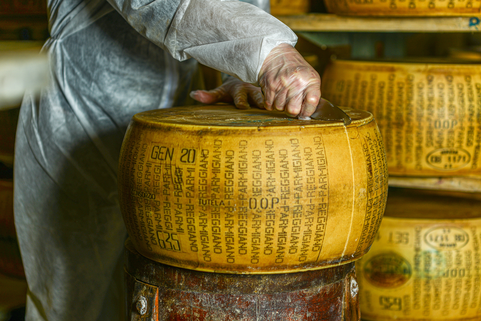 Cheese dairy master cutting a parmesan cheese wheel at the dairy (Cavan Images / Getty Images )