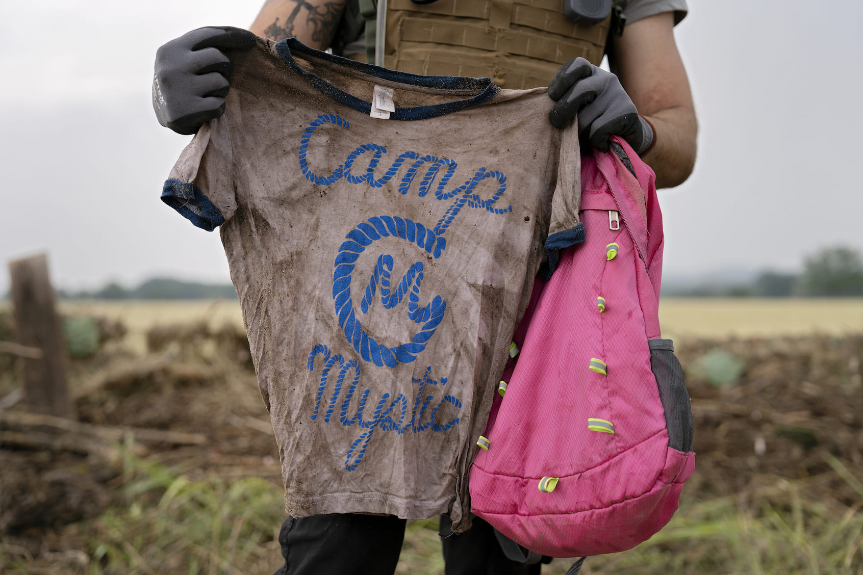 A search and rescue volunteer holds a T-shirt and backpack with the words Camp Mystic on them in Comfort, Texas. (Photo by Danielle Villasana/Getty Images)