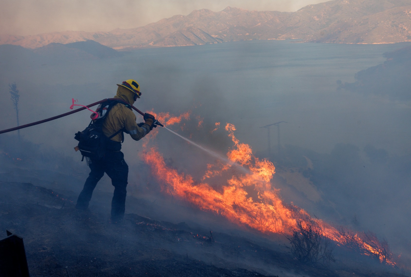 A CalFire firefighter tries to keep the Lake fire from jumping Highway 138 above the lake on June 28, 2025 in Silverwood Lake, California. (Gina Ferazzi / Los Angeles Times via Getty Images)