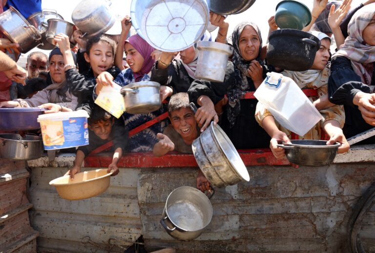 Palestinians crowd at a lentil soup distribution point in Gaza City in the northern Gaza Strip on July 27, 2025. (OMAR AL-QATTAA/AFP via Getty Images)