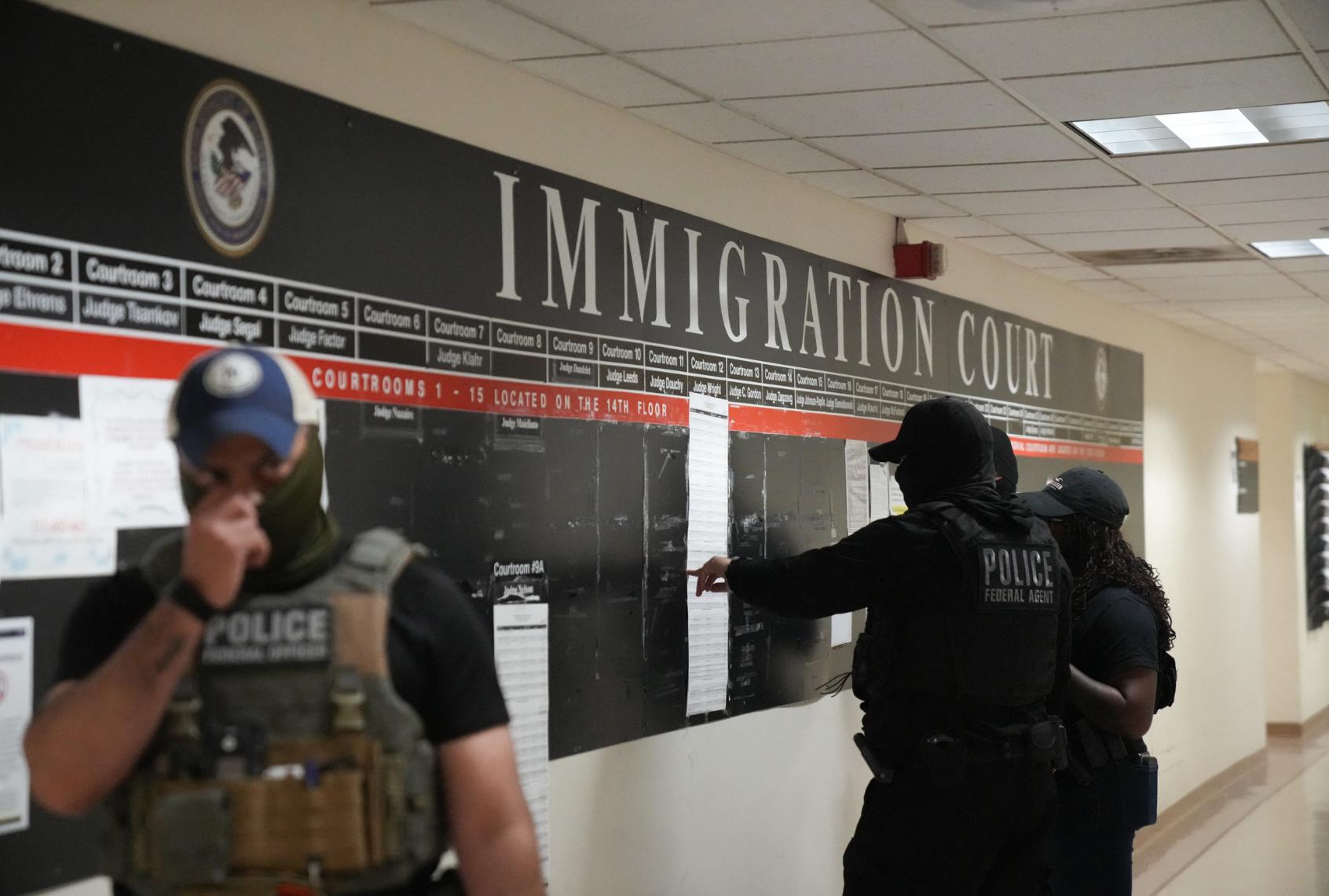 US Immigration and Customs Enforcement (ICE) agents look over lists of names and their hearing times and locations inside the Federal Plaza courthouse before making arrests on June 27, 2025 in New York. (BRYAN R. SMITH/AFP via Getty Images)