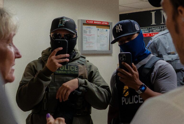 Two ICE agents film the press using smartphones in the hallway outside the immigration court  in New York USA on July 11, 2025. (MADISON SWART/Hans Lucas/AFP via Getty Images)