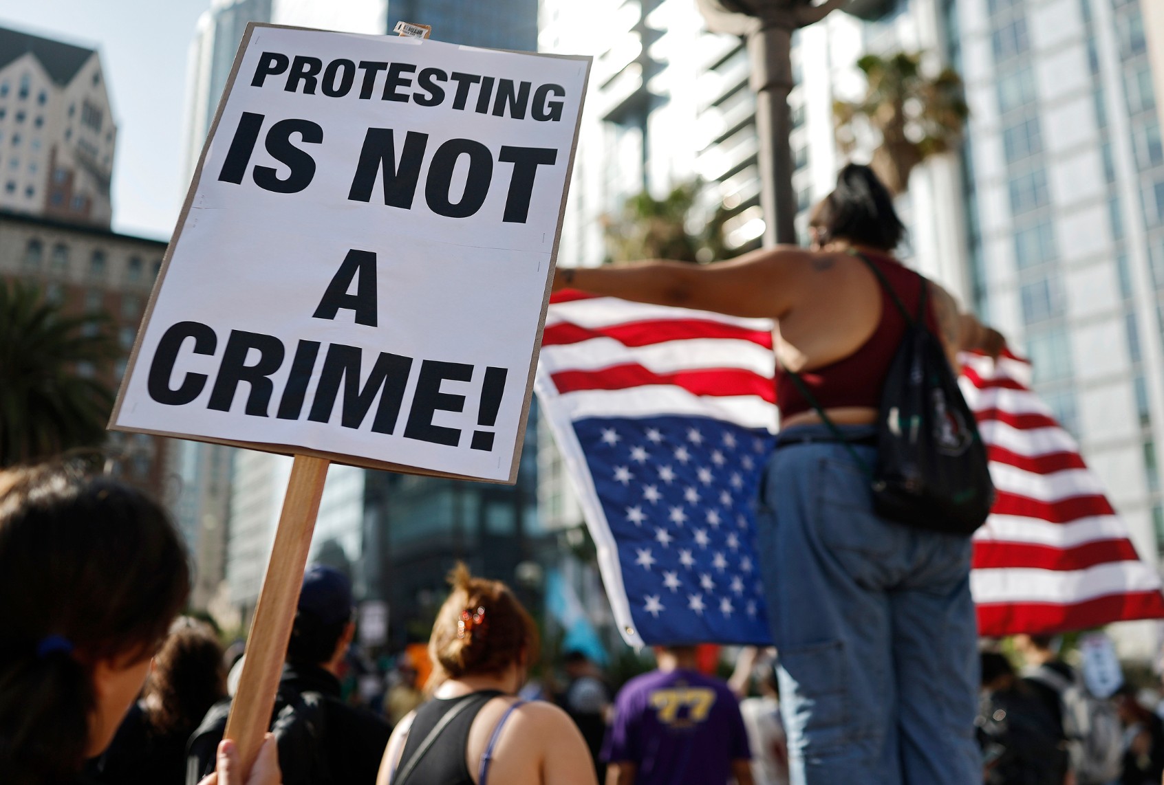 A person holds a "Protesting Is Not A Crime!" sign as people demonstrate before marching downtown as protests against ICE immigration raids continue in the city on June 11, 2025 in Los Angeles, California. (Mario Tama/Getty Images)