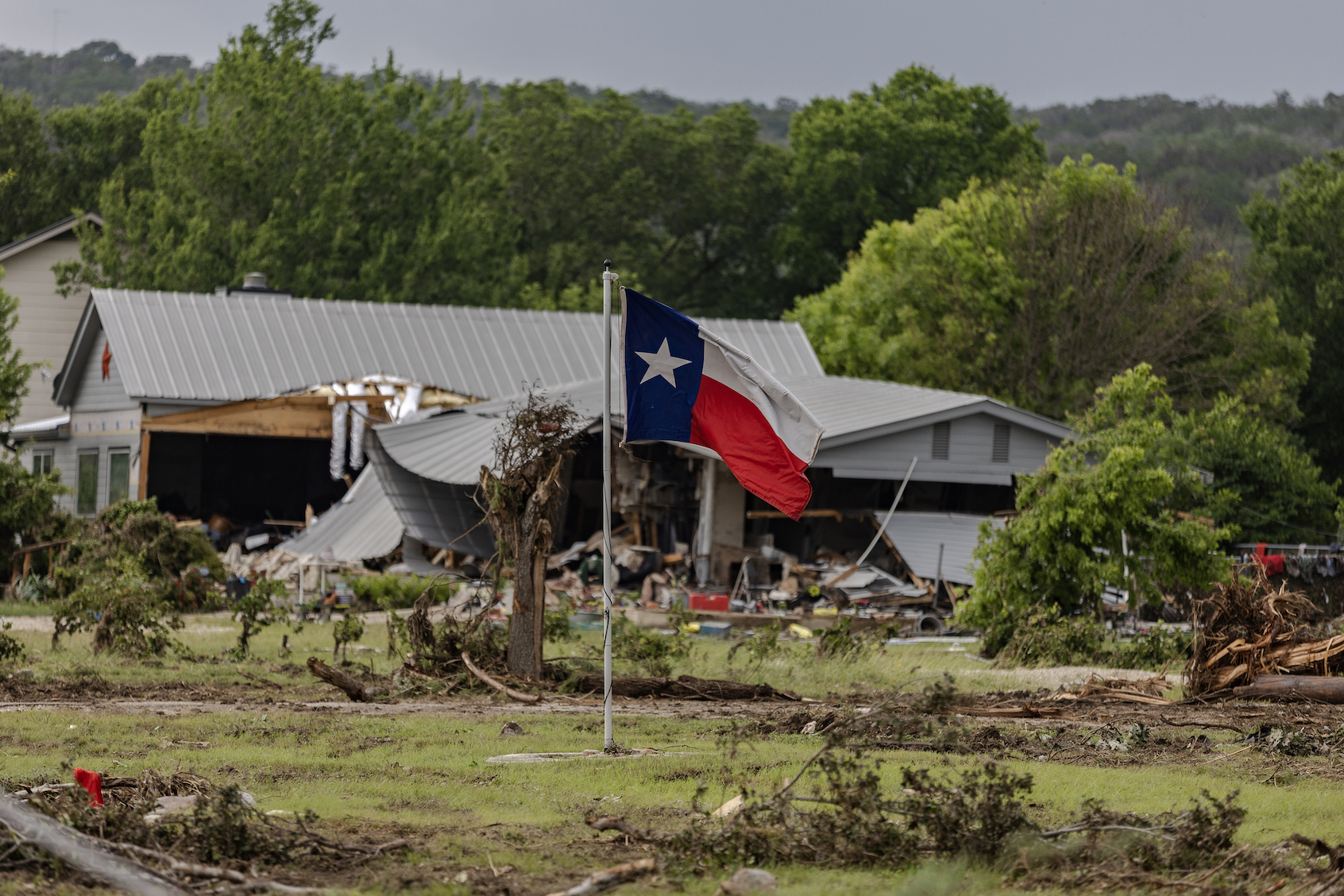 A Texas State Flag flys in a yard filled with debris on July 6, 2025 in Hunt, Texas. (Photo by Jim Vondruska/Getty Images)