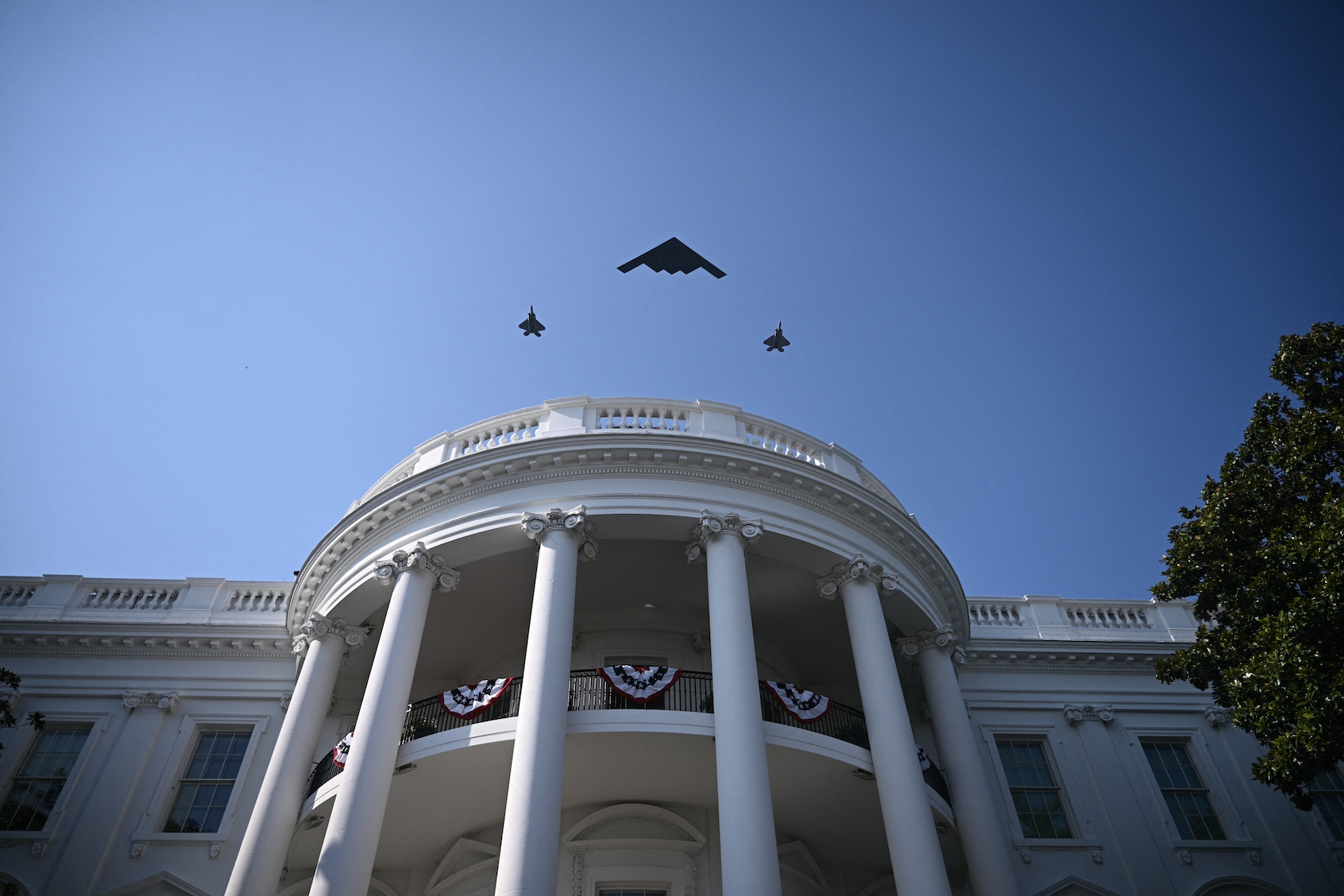 A B-2 Spirit stealth bomber escorted by 2 F-35 Lightning II stealth fighters fly over the White House as US president Donald Trump and First Lady Melania Trump participate in the Military Family Picnic on the South Lawn of the White House. ( (Photo by Brendan Smialowski/Getty Images)