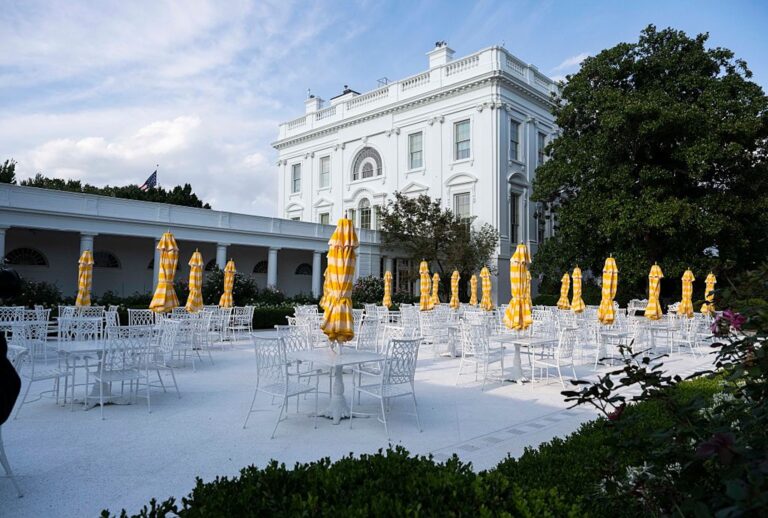 Metal tables and chairs along with yellow umbrellas decorate a paved over historic White House Rose Garden lawn on Aug. 16, 2025. (Roberto Schmidt/Getty Images)