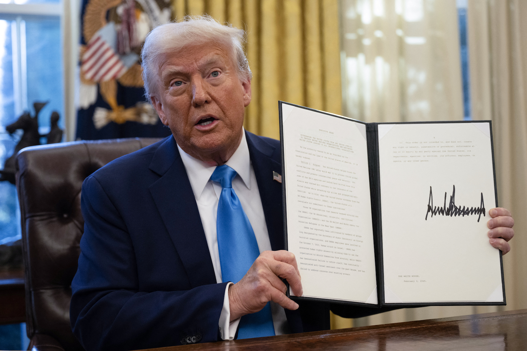 US President Donald Trump shows an executive order withdrawing his country from a number of United Nations bodies. (Photo by Andrew Caballero-Reynolds/Getty Images)