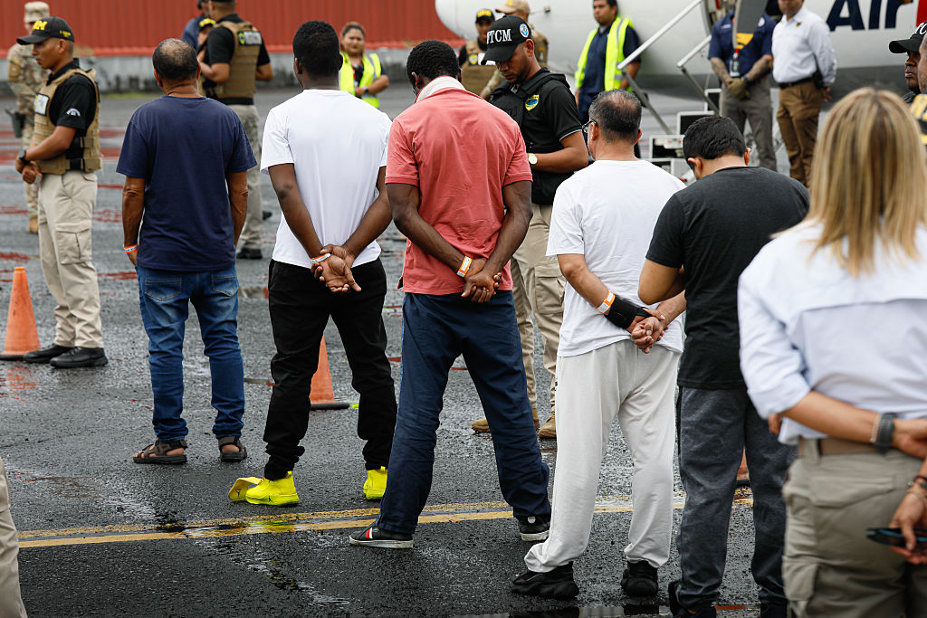 Individuals in ICE custody walk toward a deportation plane. A White House video featuring similar images and viral audio from a Jet2 ad sparked backlash. (Daniel Gonzalez / Anadolu / Getty Images)