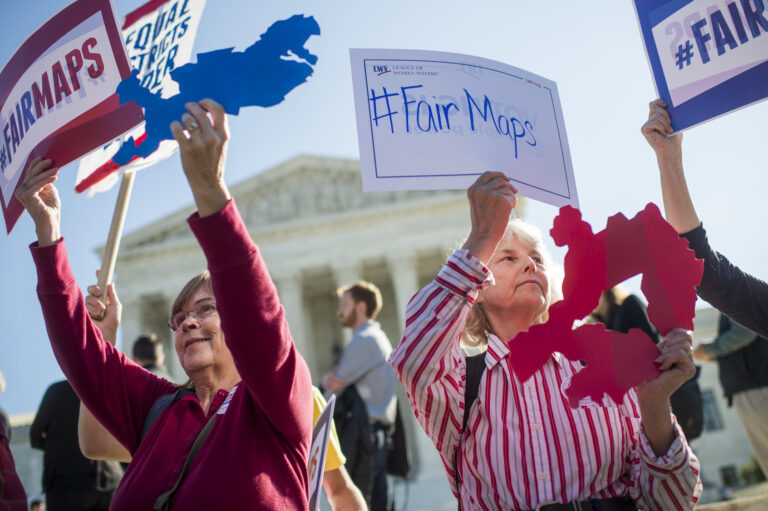 Shirley Connuck, right, holds up a sign representing a district in Texas, as the Supreme Court hears a case on partisan gerrymandering by state legislatures on October 3, 2017. (Photo By Tom Williams/Getty Images)