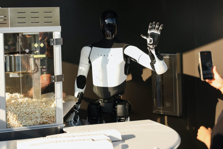 A Tesla Optimus robot scoops popcorn and waves at attendees during the opening of the Tesla Diner and Drive-In (Patrick T. Fallon / AFP / Getty Images)