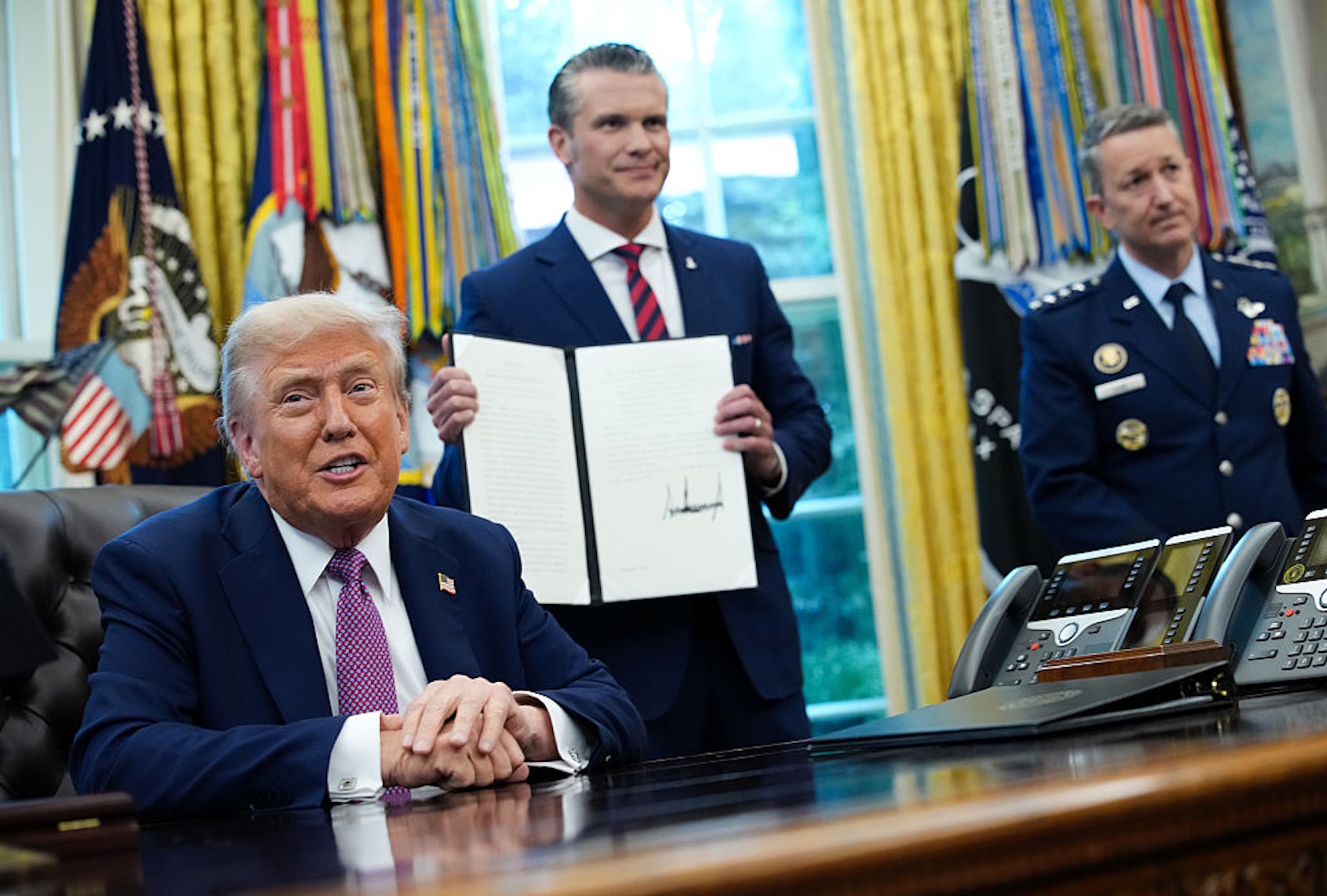 President Donald Trump speaks to the media after signing an executive order renaming the Department of Defense the Department of War as Defense Secretary Pete Hegseth and Chairman of the Joint Chiefs of Staff Air Force Gen. Dan Caine (R) look on in the Oval Office on Sept. 5, 2025. (Kevin Dietsch/Getty Images)