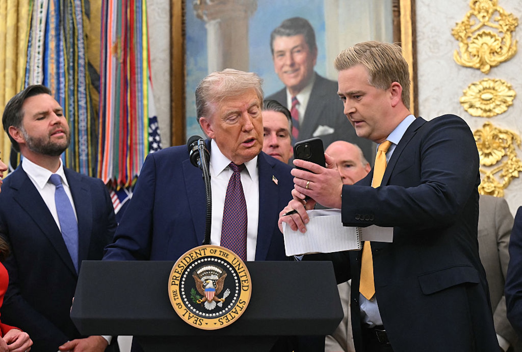 Fox News reporter Peter Doocy shows President Donald Trump his phone during an Oval Office press availability on Sept. 2, 2025. (SAUL LOEB/AFP via Getty Images)