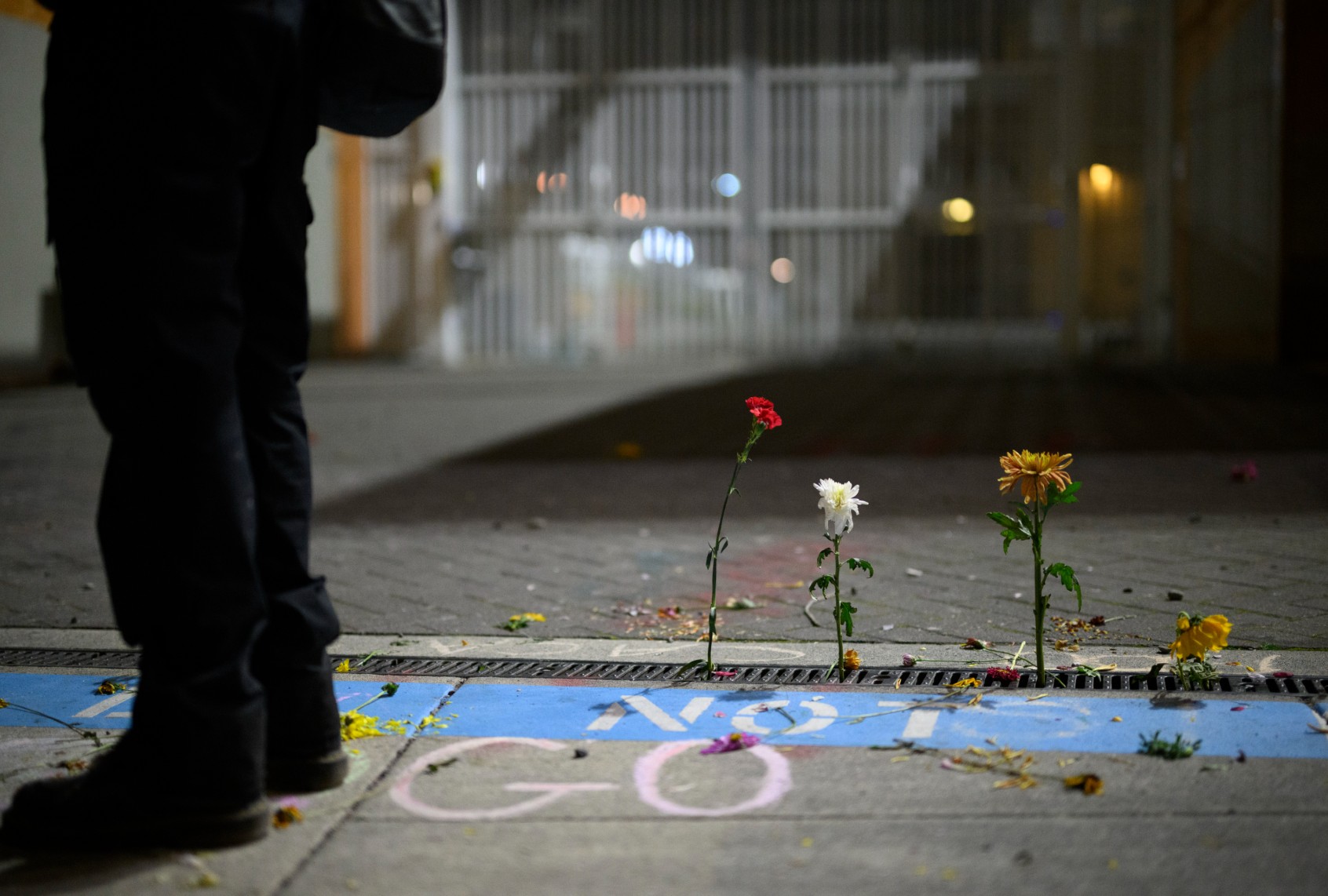 A protester stands next to flowers outside the U.S. Immigration and Customs Enforcement building on September 27, 2025 in Portland, Oregon. (Mathieu Lewis-Rolland/Getty Images)