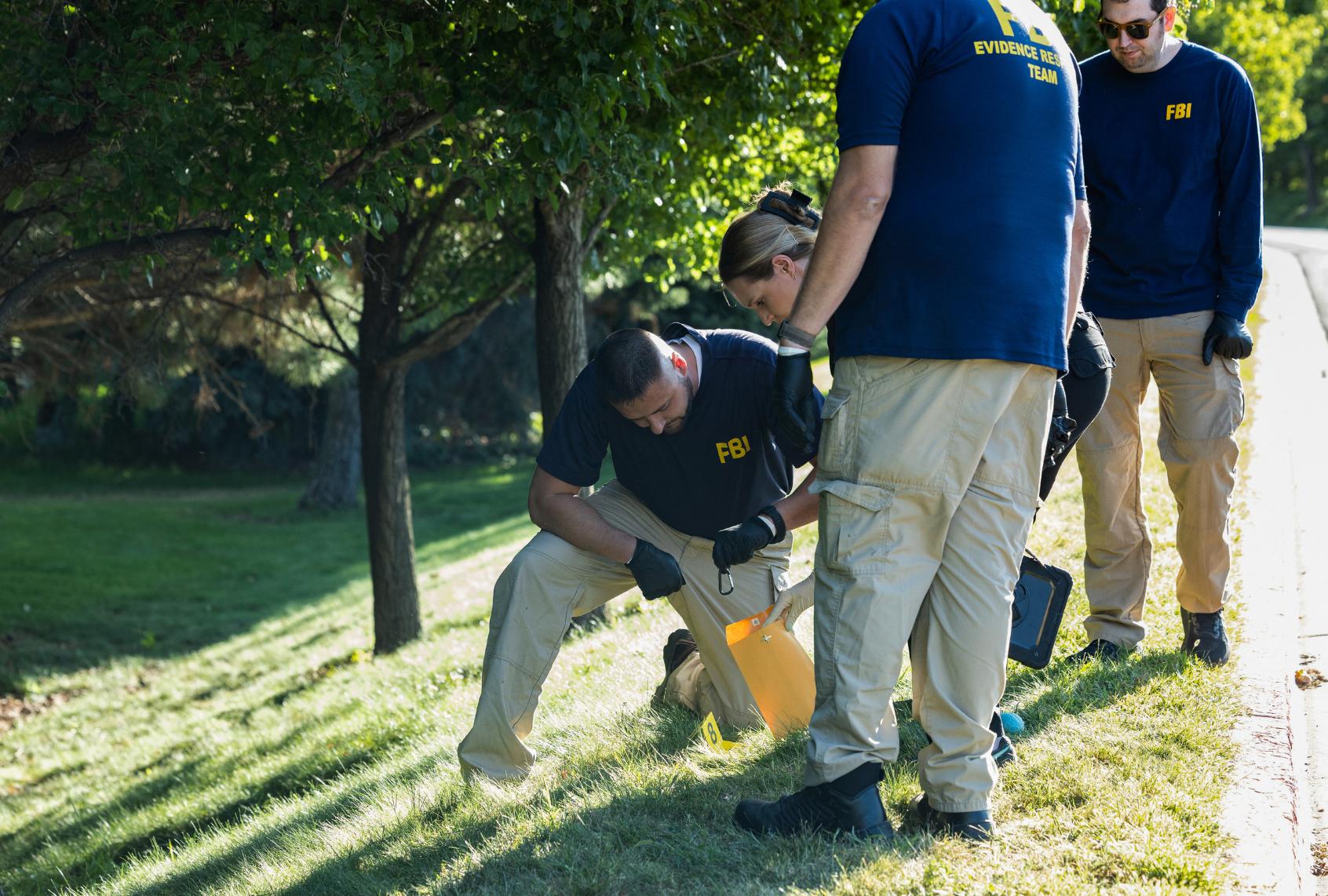 Law enforcement officials, including members of an FBI forensics team, investigate near the crime scene where political activist Charlie Kirk was shot and killed at Utah Valley University in Orem, Utah, on September 11, 2025. (MELISSA MAJCHRZAK/AFP via Getty Images)
