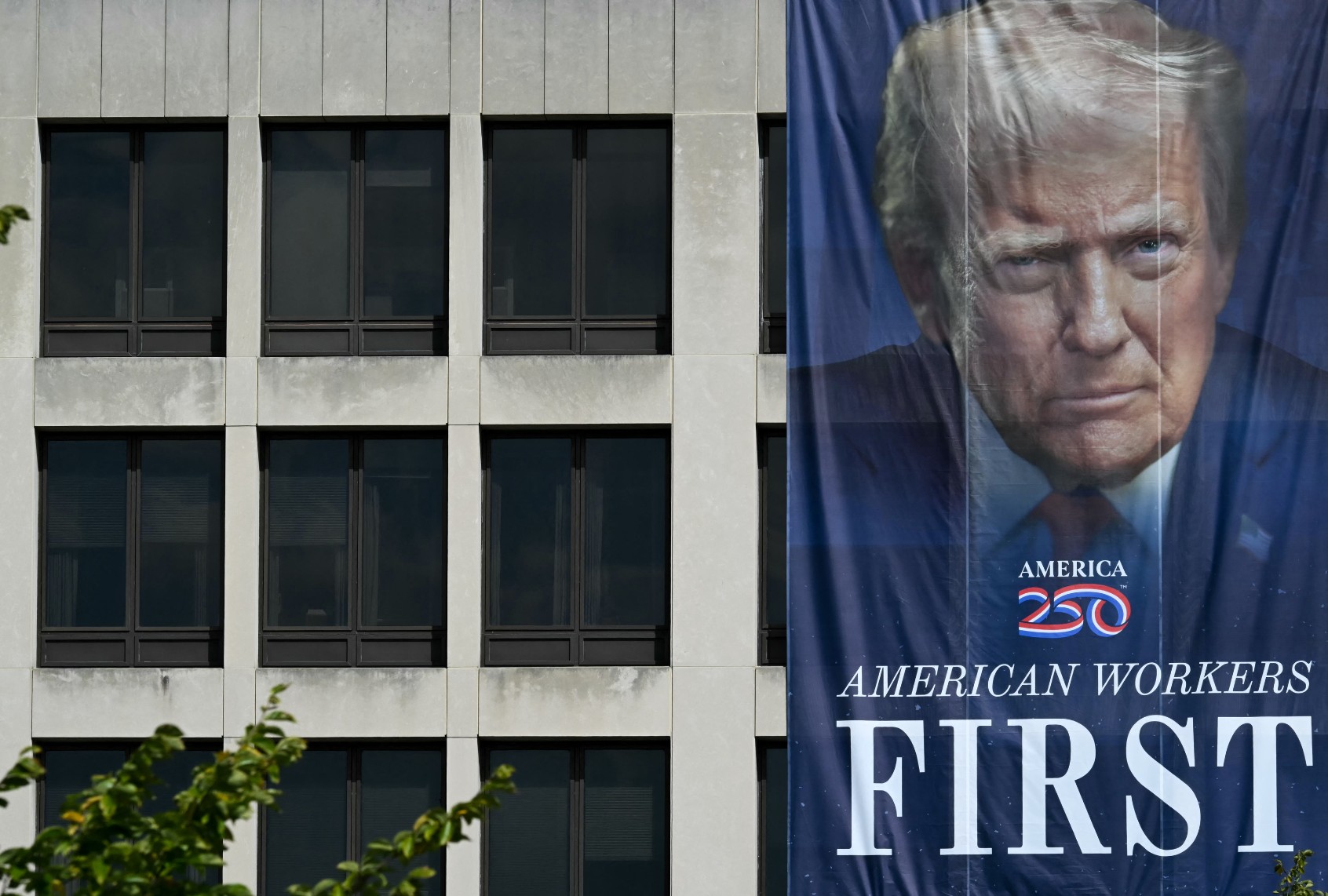 An image of US President Donald Trump hangs on the outside of the Department of Labor headquarters building in Washington, DC on October 7, 2025. (ANDREW CABALLERO-REYNOLDS/AFP via Getty Images)