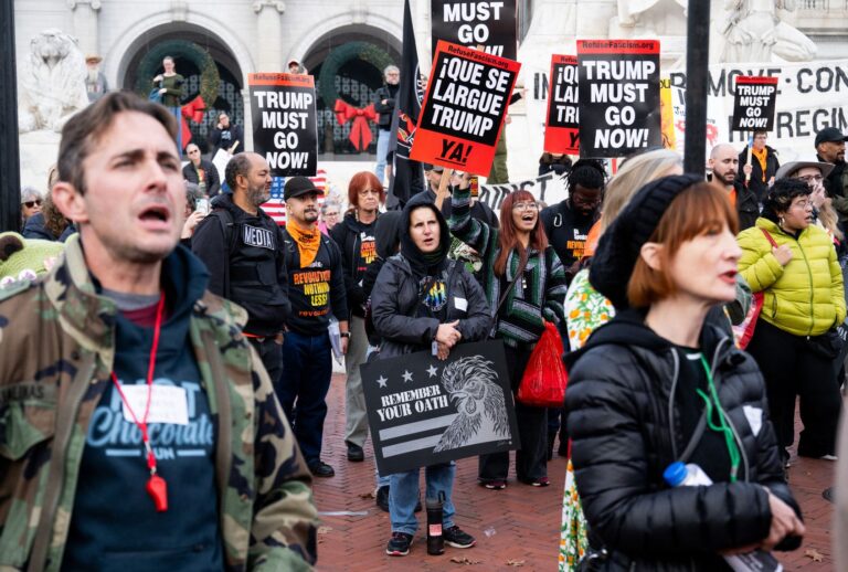 Demonstrators hold signs during the "Remove the Regime" protests against President Donald Trump in Washington, DC, on November 21, 2025. (SAUL LOEB / AFP via Getty Images)