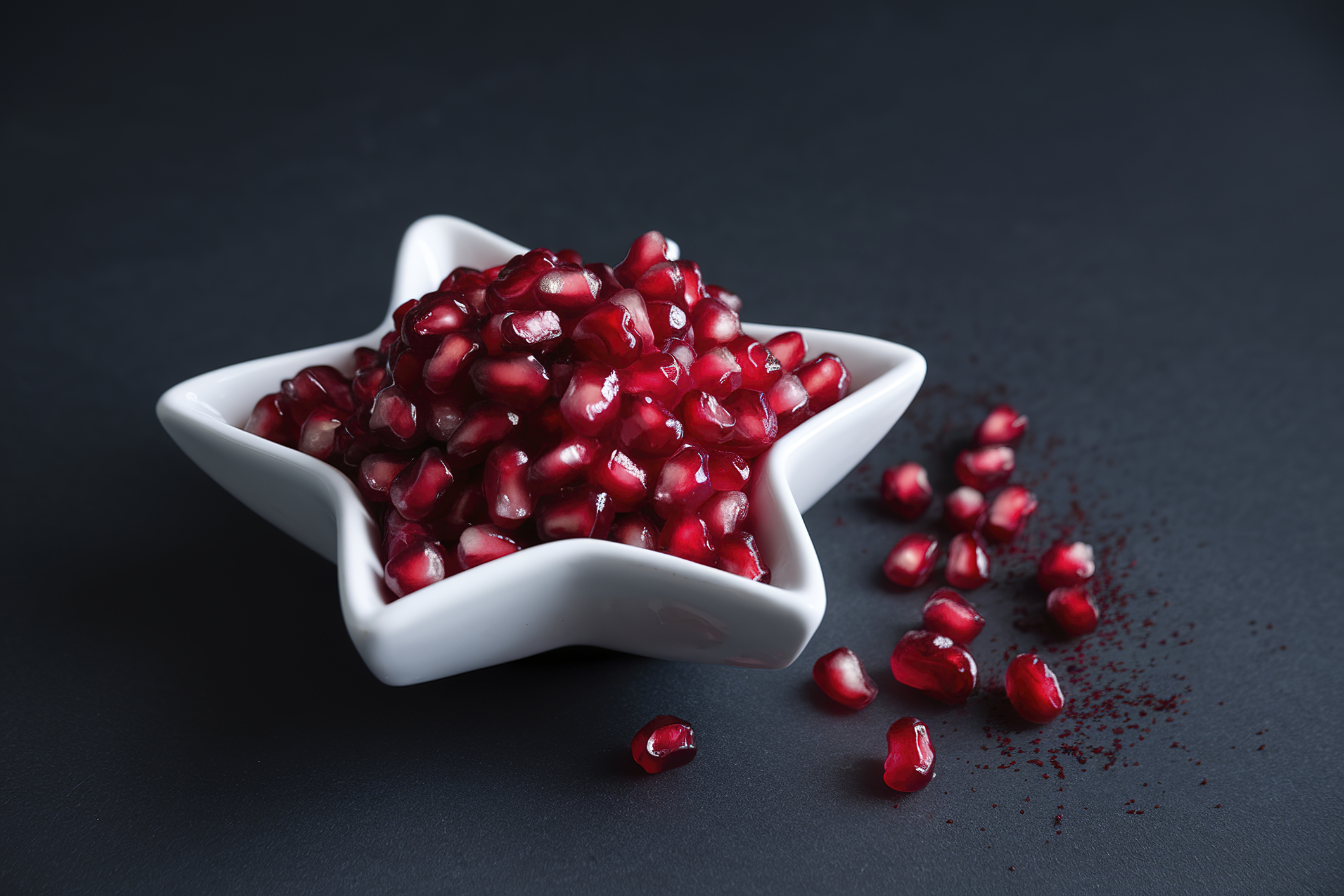 A white star-shaped bowl filled with fresh red pomegranate seeds (Horia Ionescu / 500px / Getty Images)