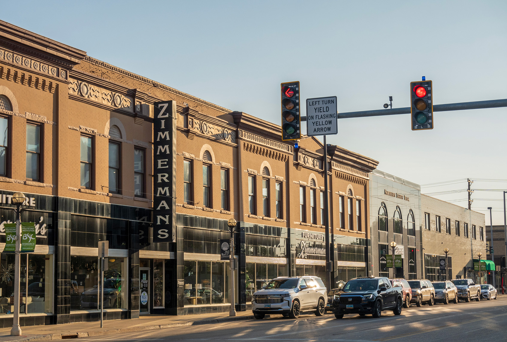 Historic storefronts line a downtown street in Bismarck, North Dakota, with cars parked along the curb.