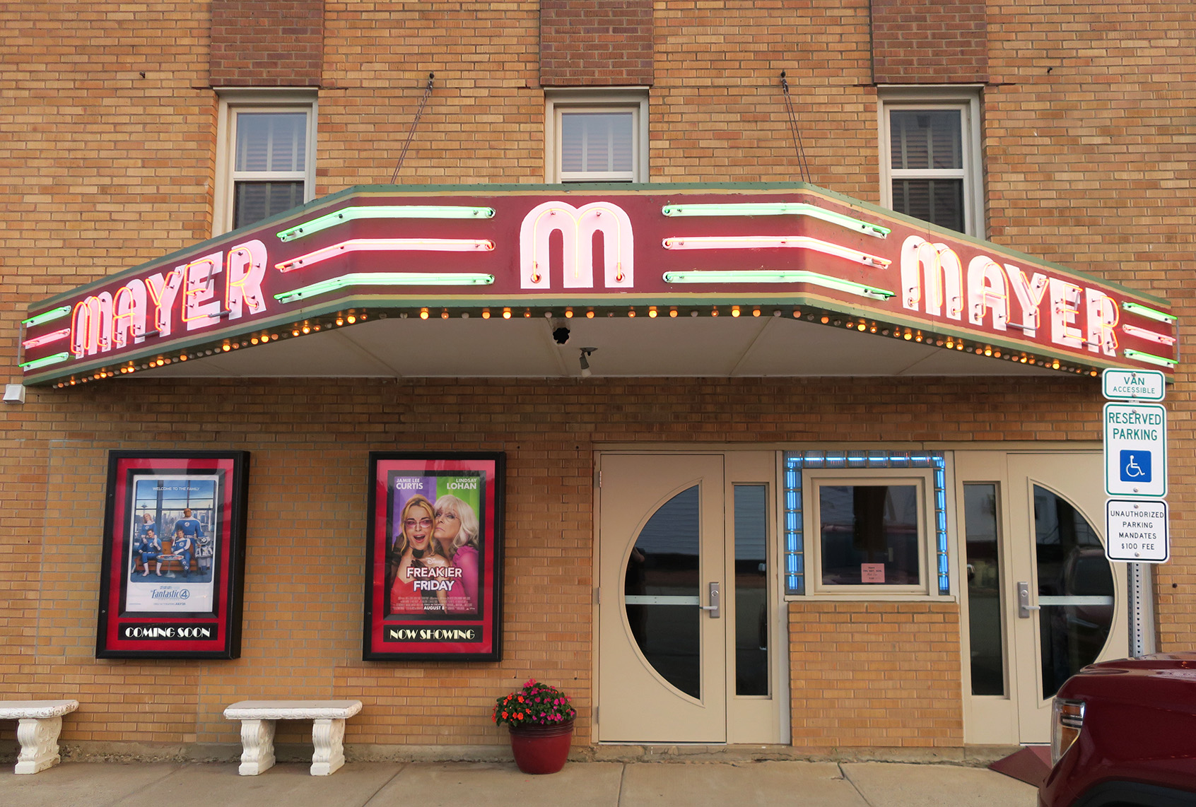 The Mayer Theatre exterior, featuring a glowing marquee and movie posters by the doors.