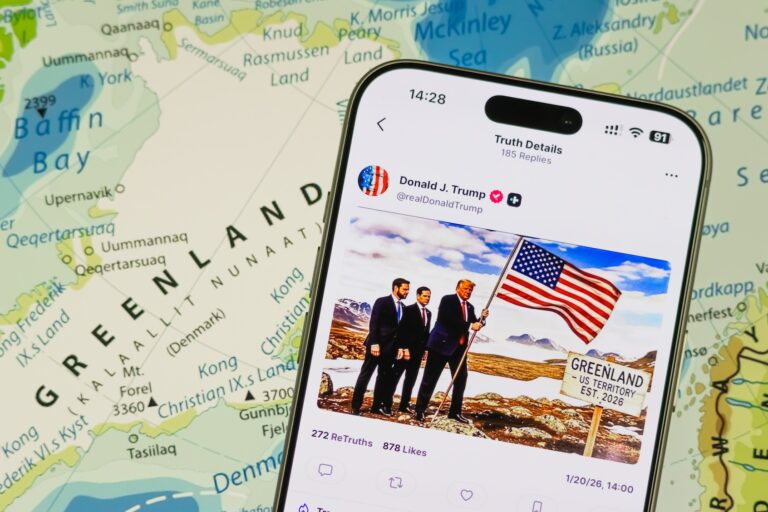 This photo illustration displays a post by Donald Trump on Truth Social, with a map of Greenland in the background. (Photo illustration by Cheng Xin/Getty Images)