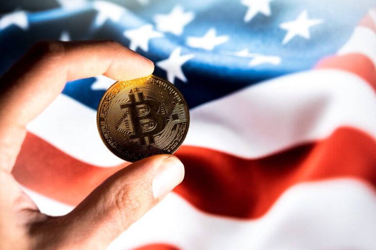 A physical representation of Bitcoin and the flag of the United States (U.S.) appear as the background on a laptop computer screen in this photo illustration in Athens, Greece, on January 13, 2026. (Photo by Nikolas Kokovlis/Getty Images)