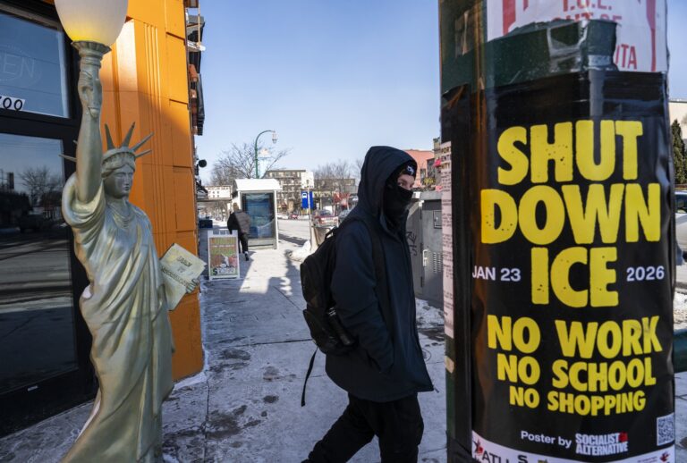 A person walks past a Lady Liberty statue in front of a shuttered gyro shop and a poster calling for a strike of businesses under the banner "ICE out of Minnesota: Day of Truth and Freedom" in Minneapolis, Minnesota, on January 23, 2026. (Photo by ROBERTO SCHMIDT / AFP via Getty Images)