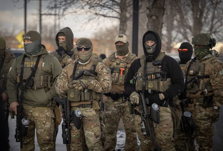 ICE Police watch as Rep. Ilhan Omar, center, U.S. Representative Kelly Morrison, left, and U.S. Representative Angie Craig, (not shown) on right, make their way into the the entrance of the Whipple Federal Building in Fort Snelling, MN on Saturday, Jan. 10, 2026. (Elizabeth Flores / Getty Images)