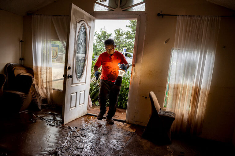 A pastor inspects his church after the floods recede on Oahu. The mud covering the floor and the high watermarks on the walls and curtains are the remnants of the historic flash floods in the area. (Stephen Lam / Getty Images)