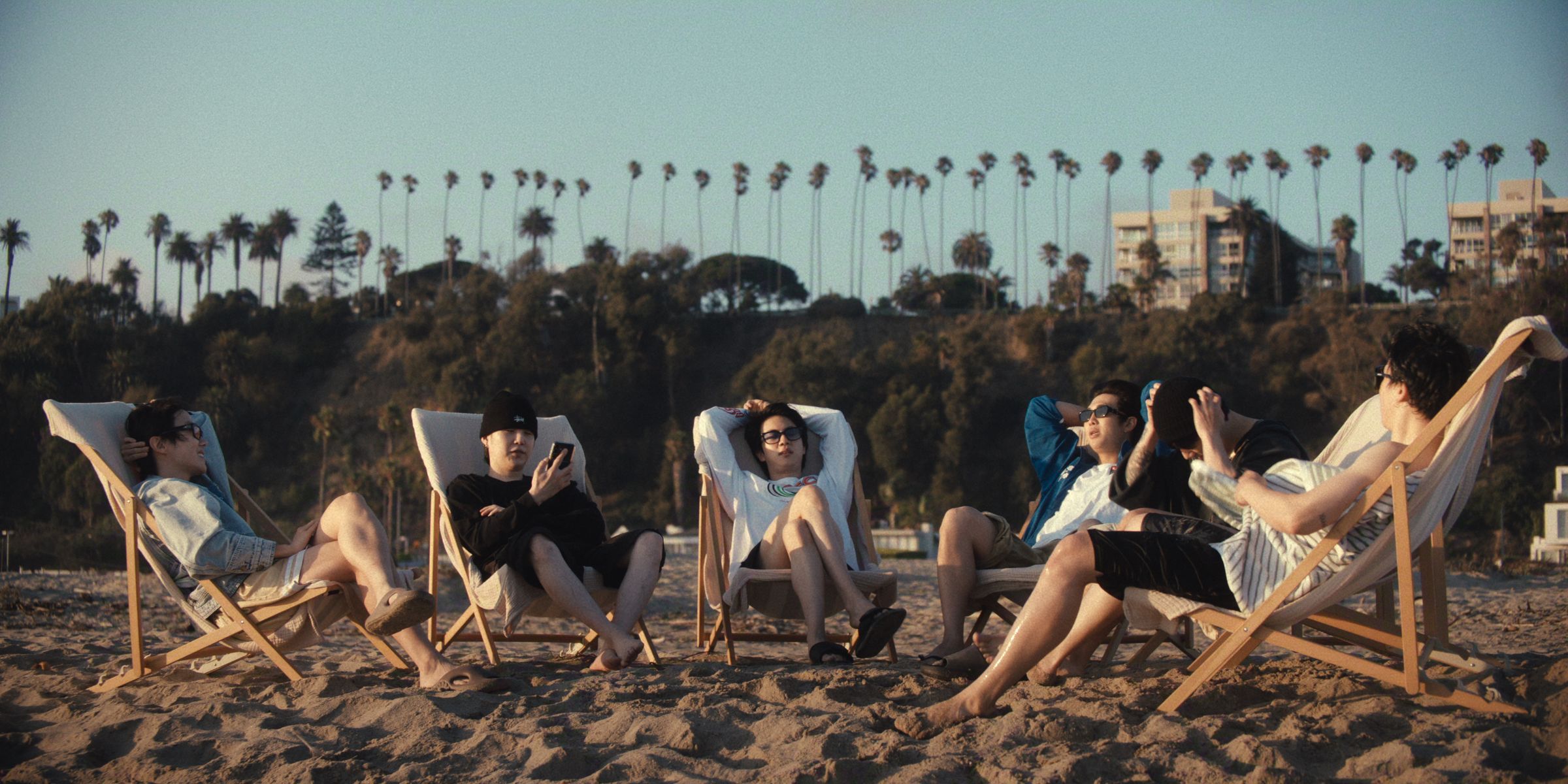 Six men chat with each other in low beach chair at the beach