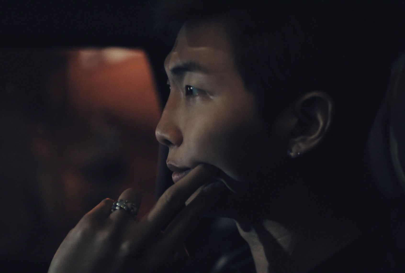 A man looks contemplatively in a shadowed car