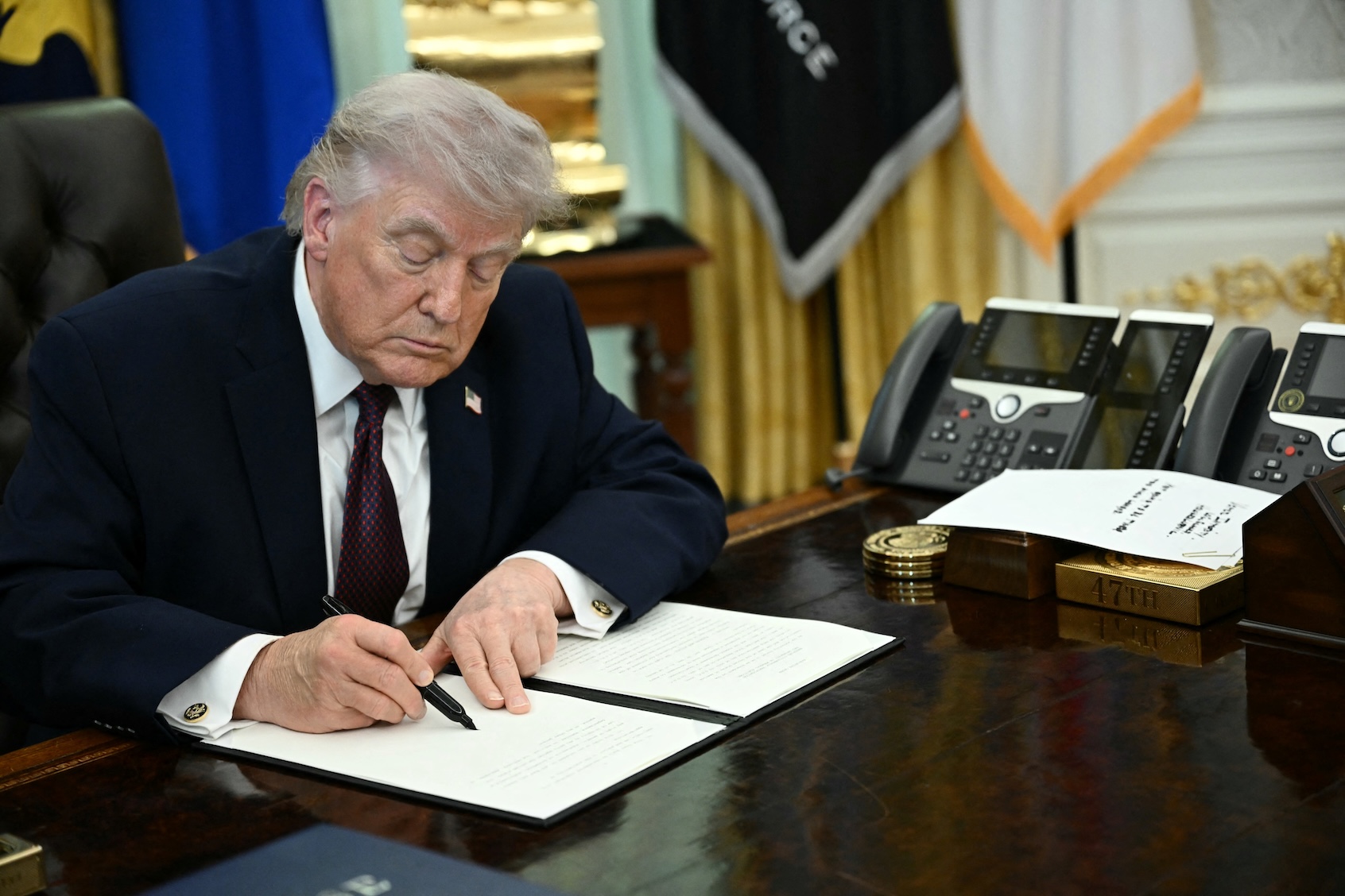 US President Donald Trump signs an executive order cracking down on mail-in voting ahead of midterm elections in the Oval Office of the White House in Washington, DC, on March 31, 2026. (Photo by Brendan Smialowski/Getty Images)