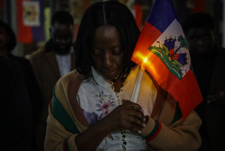 A woman prays during a candlelight vigil for Haitians living in the US under the TPS immigration program in Miami, Florida on February 3, 2026. (Photo by Giorgio Viera / AFP via Getty Images)