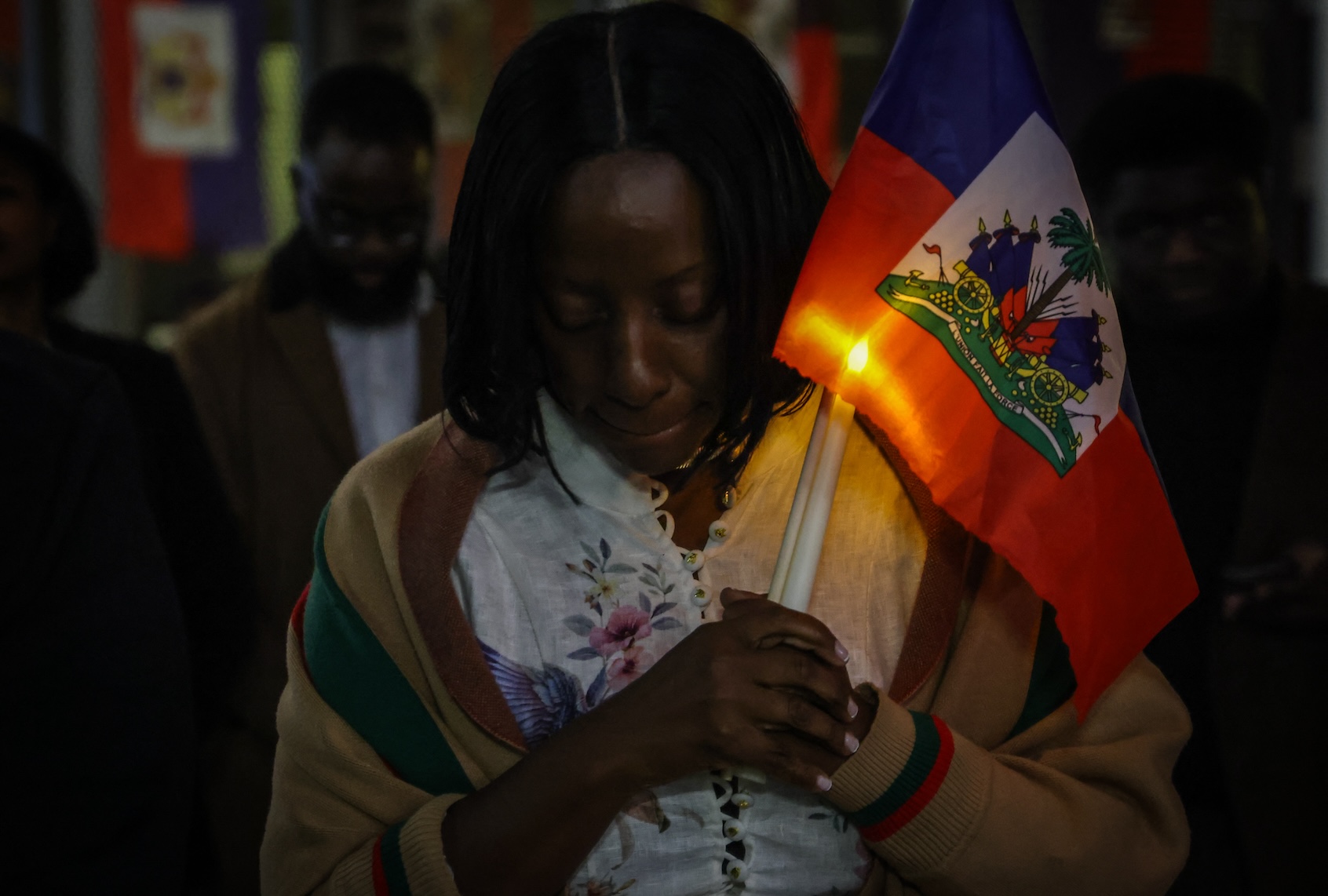 A woman prays during a candlelight vigil for Haitians living in the US under the TPS immigration program in Miami, Florida on February 3, 2026. (Photo by Giorgio Viera / AFP via Getty Images)