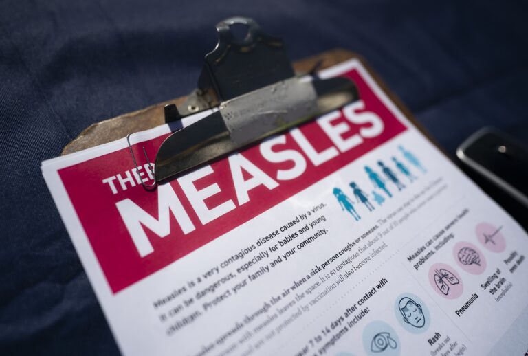 A fact sheet for measles sits on a table at a mobile clinic offering free vaccinations on February 6, 2026 in Spartanburg, South Carolina. The clinic offered free MMR vaccinations as the South Carolina Department of Health  reported 876 cases of measles earlier in the week, most centered in Spartanburg County. (Photo by Sean Rayford/Getty Images)